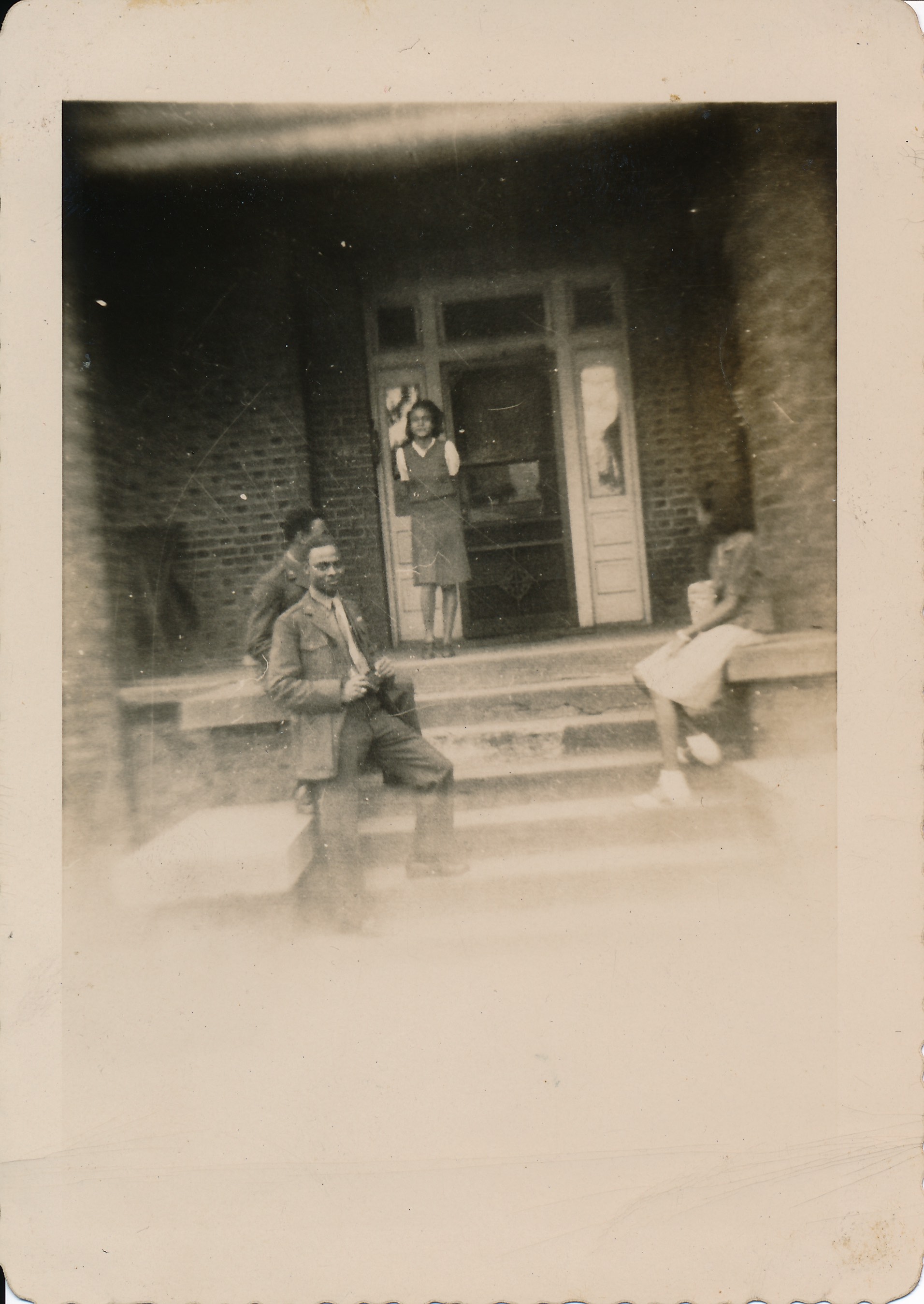 Gloria Griswold Jeffers standing in the front door of the Lewis Hotel with unidentified military personnel and woman, undated