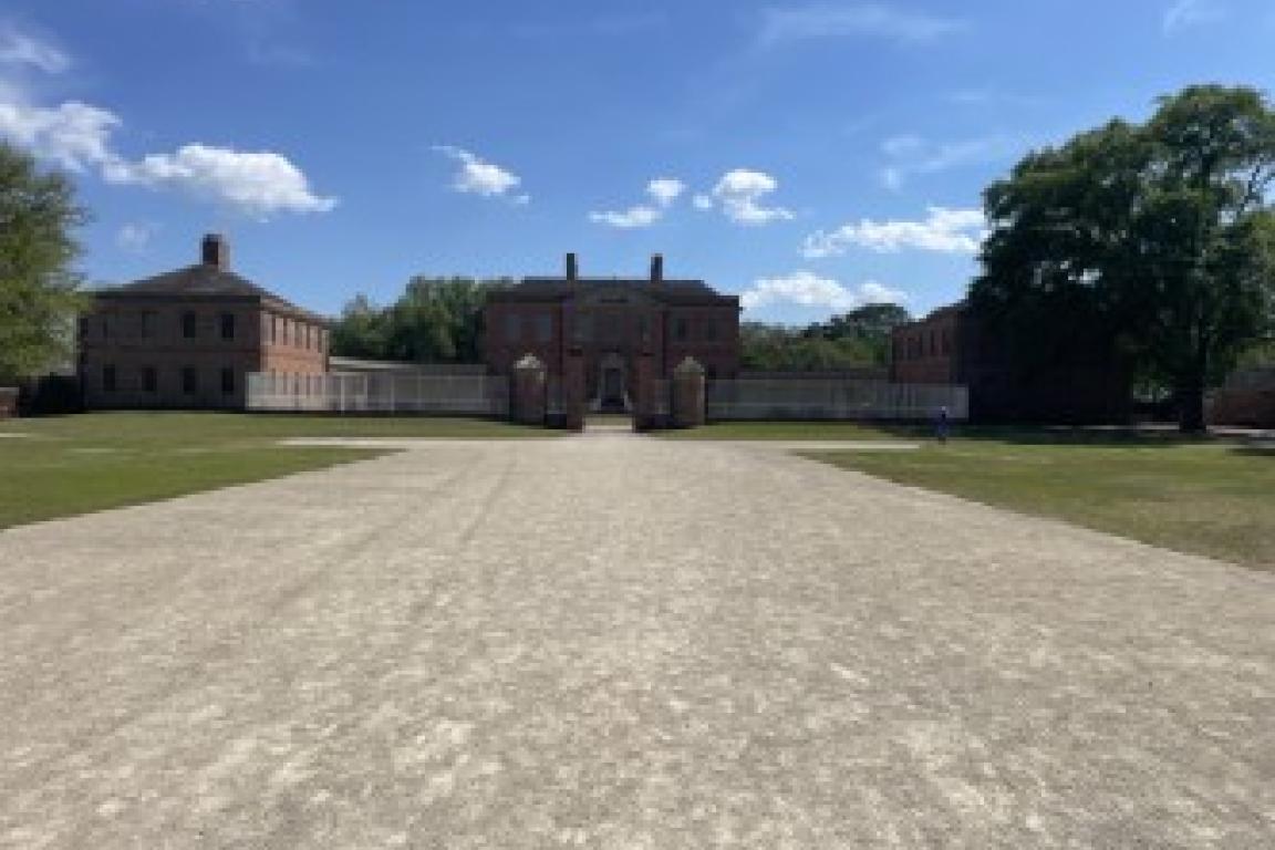 Far sighted image of Tryon Palace. Large walkway leading to a distant gate and mansion
