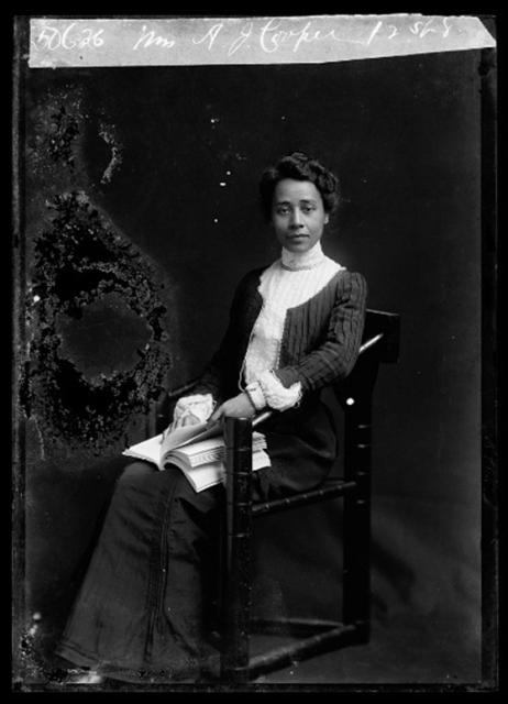 Dr. Anna Julia Cooper sitting posed in a chair, holding a book.
