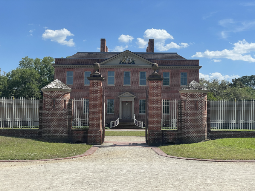 Entrance of Tryon Palace. Paved walkway with a brick gate and fence with a brick mansion