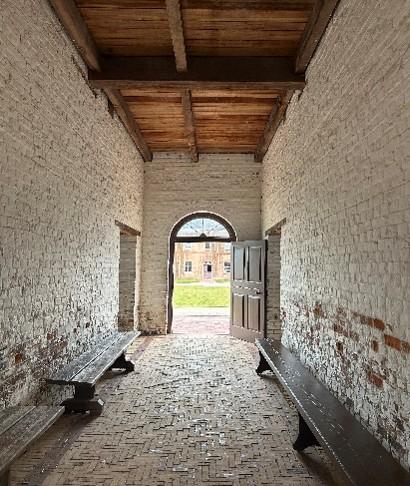 A brick entry way with an open door and wooden benches along the side