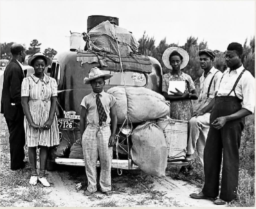 People stand around packed car in 1930's