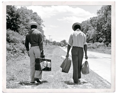 two men walk along side of highway with suitcases
