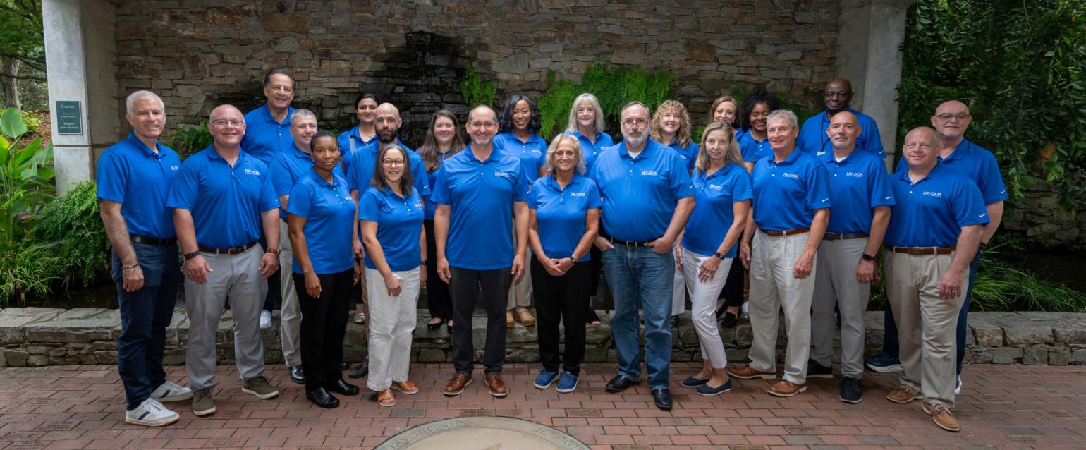 Photo of the DOA Executive Leadership team in blue shirts. Dated August 2026. 