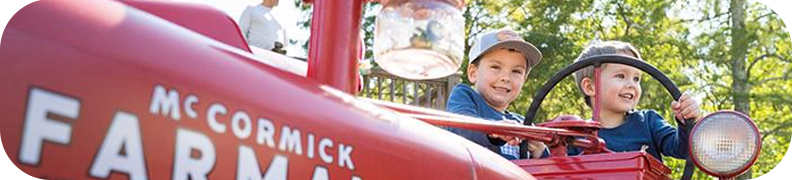 Two young kids sitting on an antique tractor