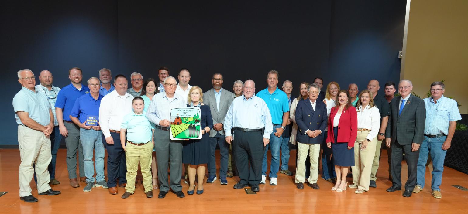 A group of people pose for a photo on a stage.