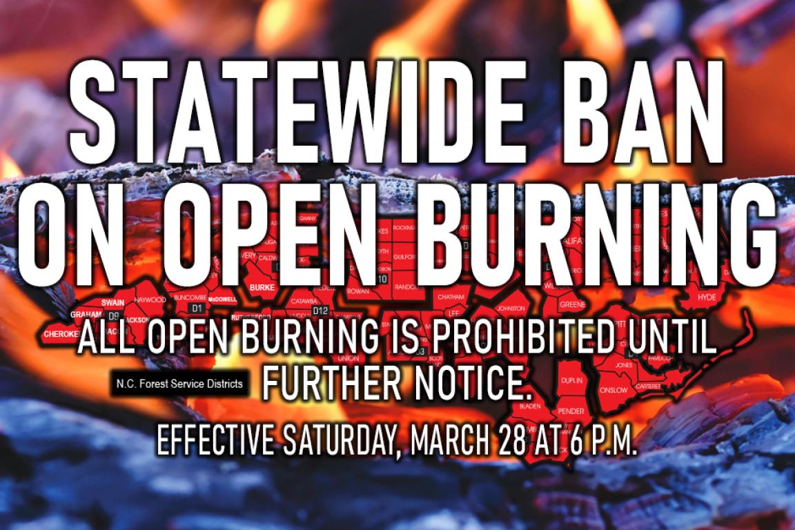 Red-hot ashes behind a notice of a burn ban starting at 6 p.m March 28
