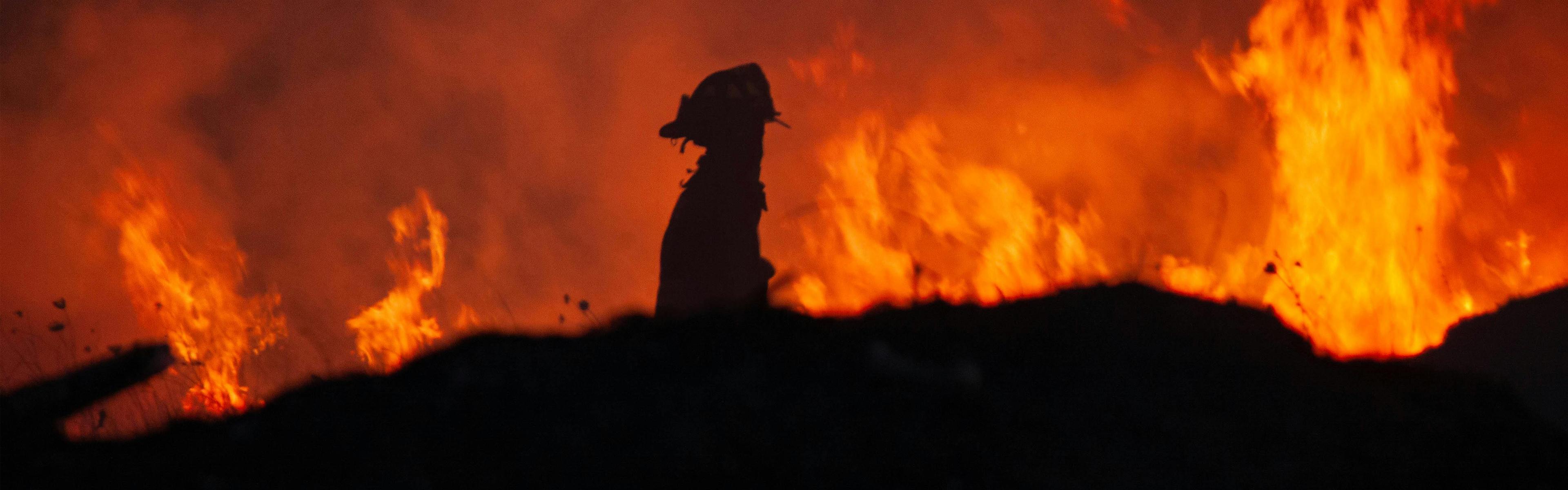 SIlhouette of a firefighter with fire in the background