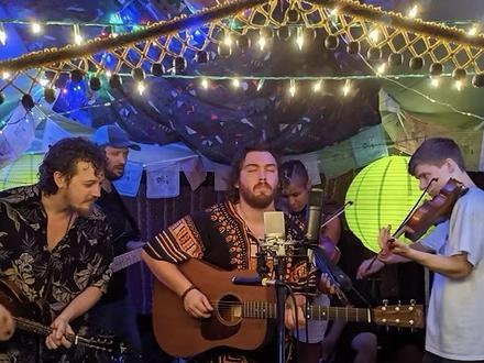 Group of men playing instruments under string lights