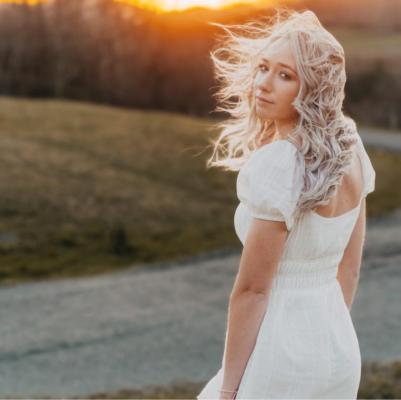 Girl standing in a field at sunset