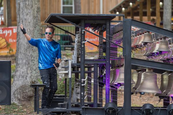 Man in blue shirt standing playing a carillon. 
