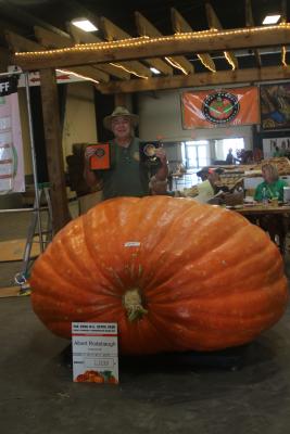 A man posing with a 2,000 pound pumpkin