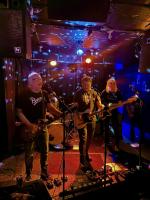 Three men playing guitars and singing on stage