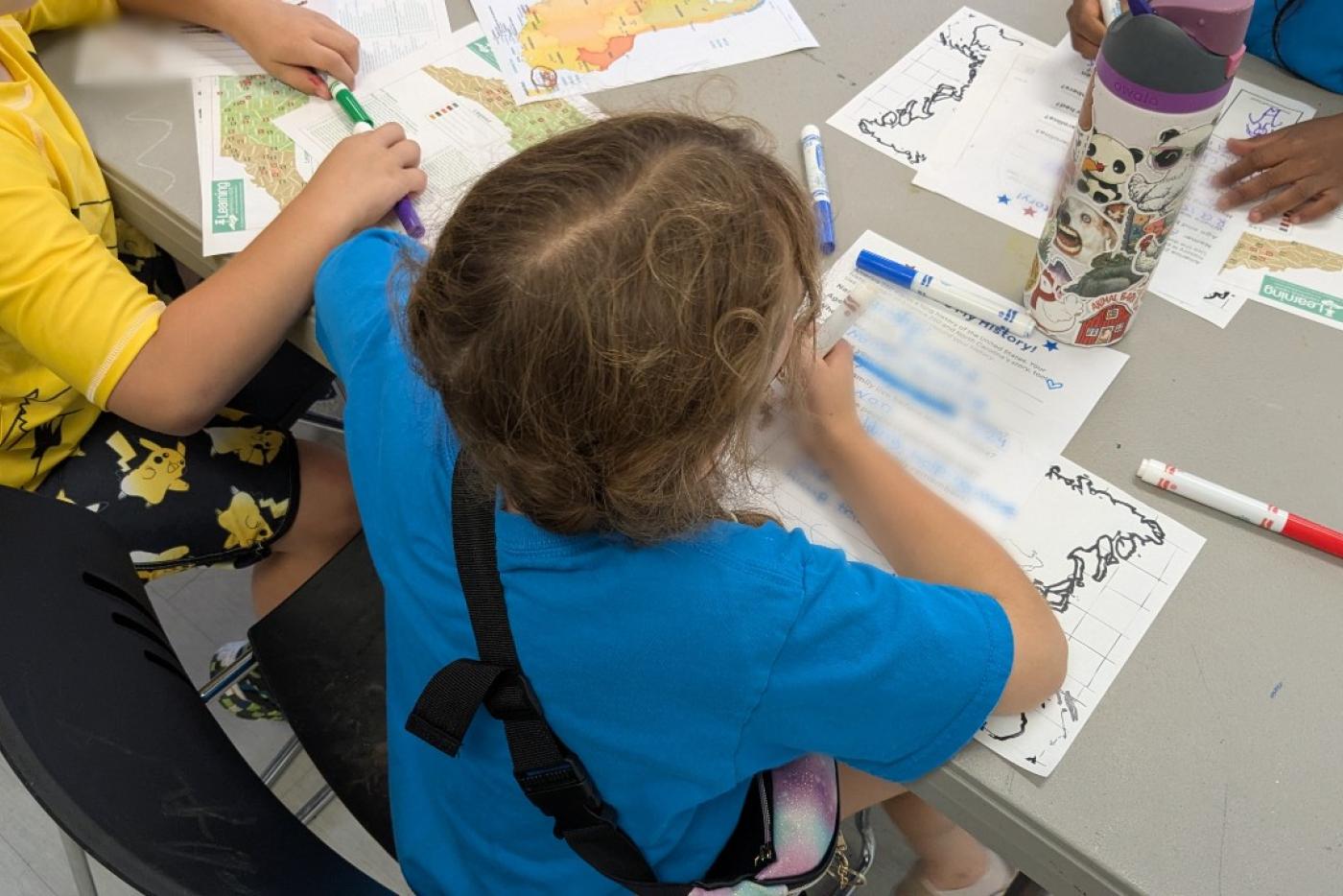 Students filling out worksheets with colorful markers