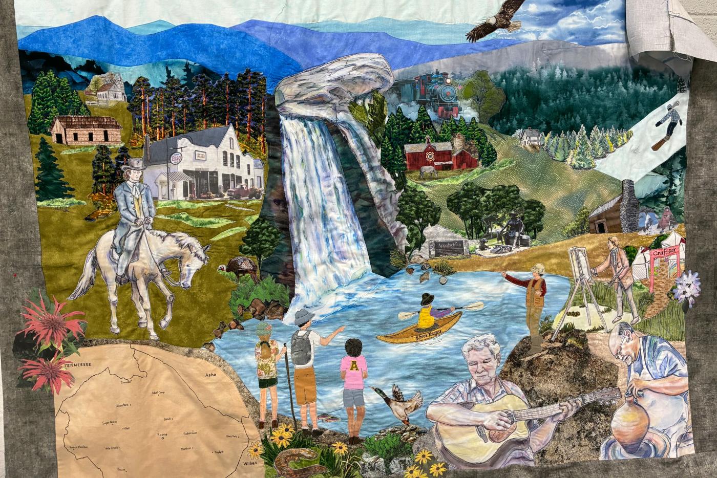 decorative quilt depicting historic scenes. Water down the middle, waterfall, people in the body of water, man on horse, nature scene with mountains in background.