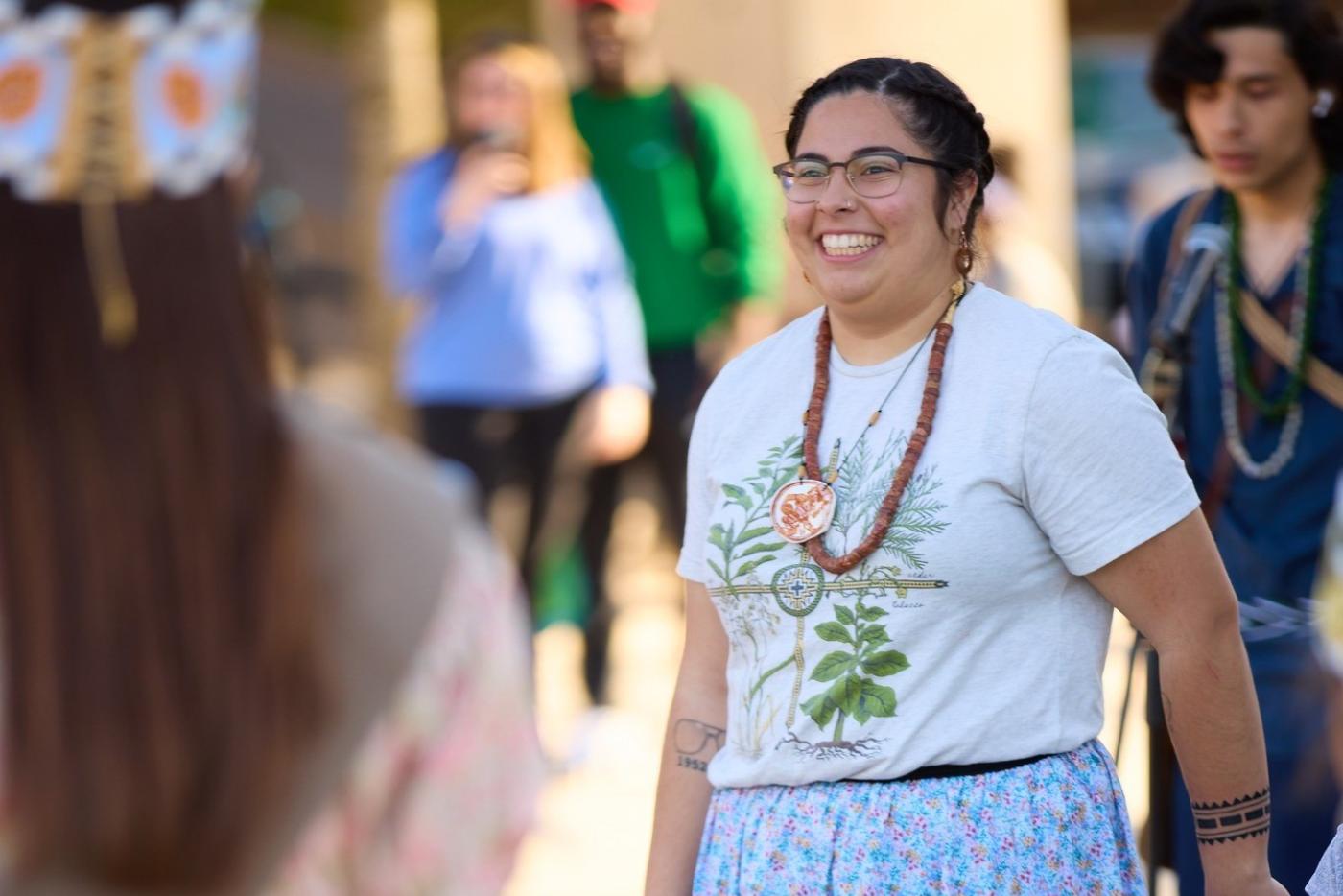 A woman smiling wearing traditional Indigenous celebration clothing.