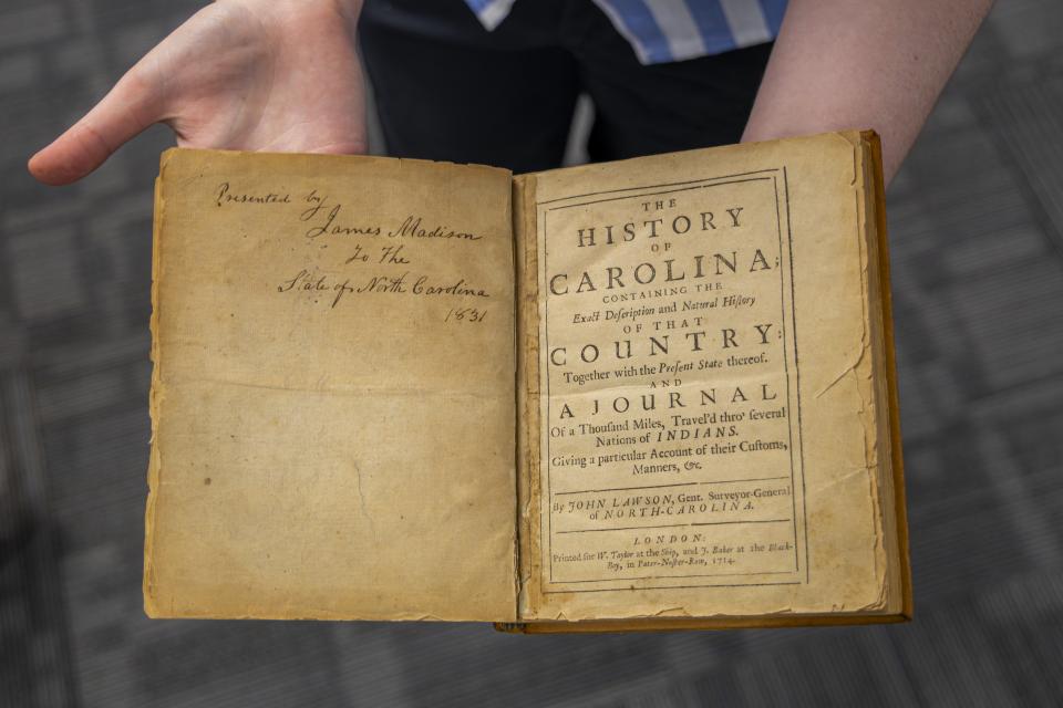 hands holding open a historic book that is signed