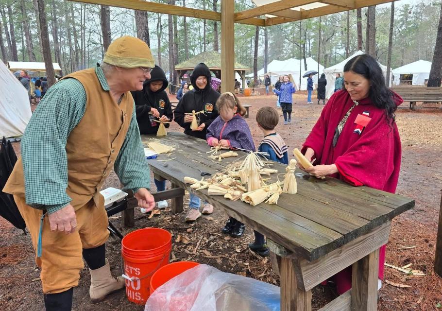 crowd around a table making cornhusk dolls