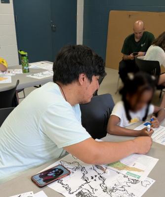 Team member assisting young child with filling out worksheet