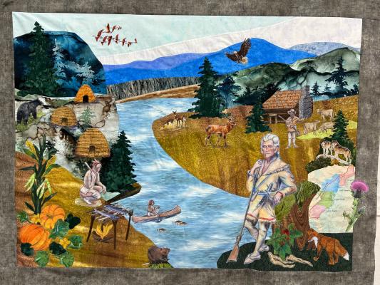 decorative quilt depicting historic scenes. Water down the middle, man to the right, mountains in the background.