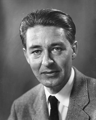 black and white portrait of a man looking at the camera, wearing a suit, slick back hear