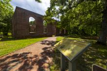 Ruins of St. Philips Anglican Church in colonial Brunswick Town surrounded by green leafy trees.