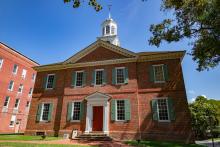 A historic brick courthouse with a white wooden cupola featuring a green roof and iron weathervane.