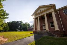 The red brick Elliot Hall sits on the campus of the Palmer Memorial Institute on a sunny day.