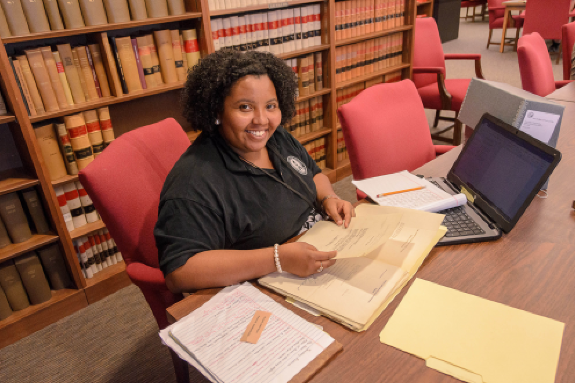 Researcher sitting at a table in the search room with archival materials and a computer