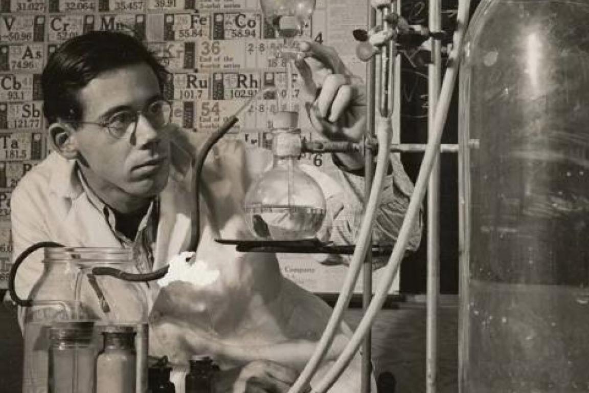 Person wearing glasses using beakers connected to a tank in a chemistry lab