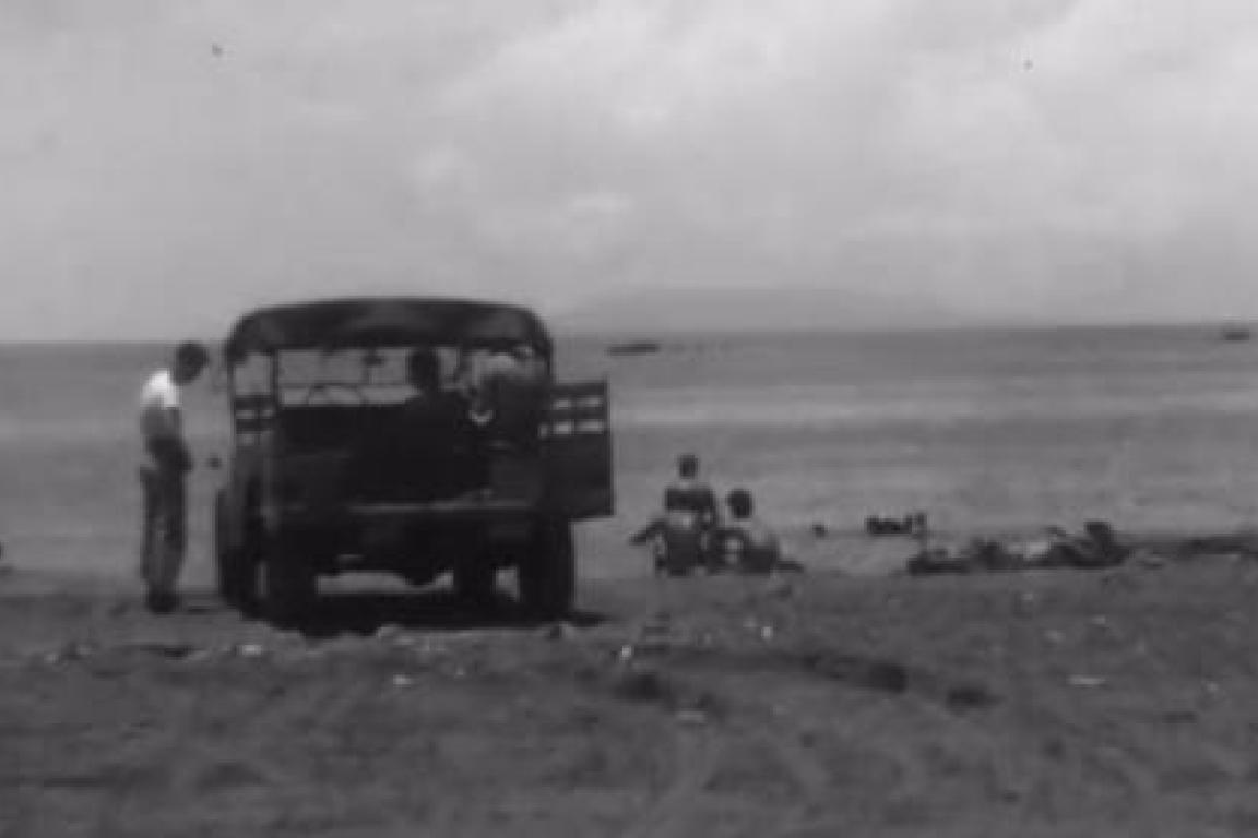 Man standing next to truck in front of the ocean horizon