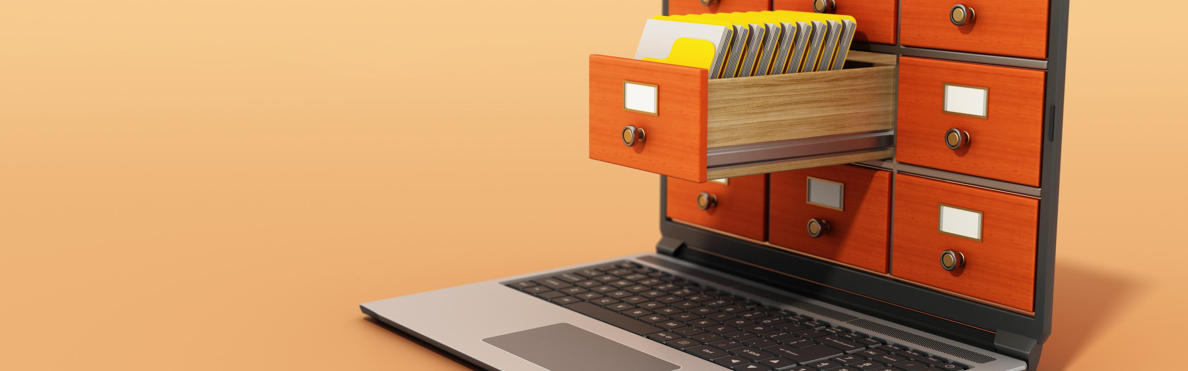 An open laptop, but where the screen should be are instead the drawers of a wooden card catalog containing hard drives. 