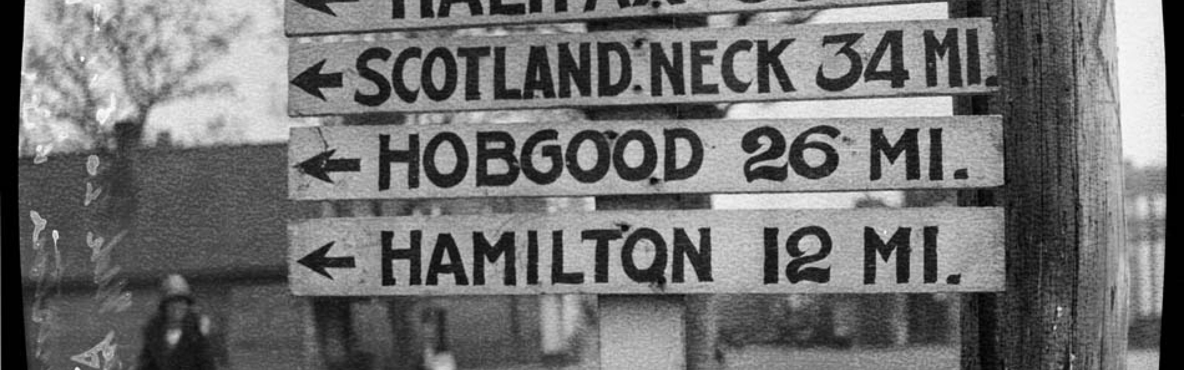Sign for mileage to cities including Halifax, Scotland Neck, Hobgood, and Hamilton