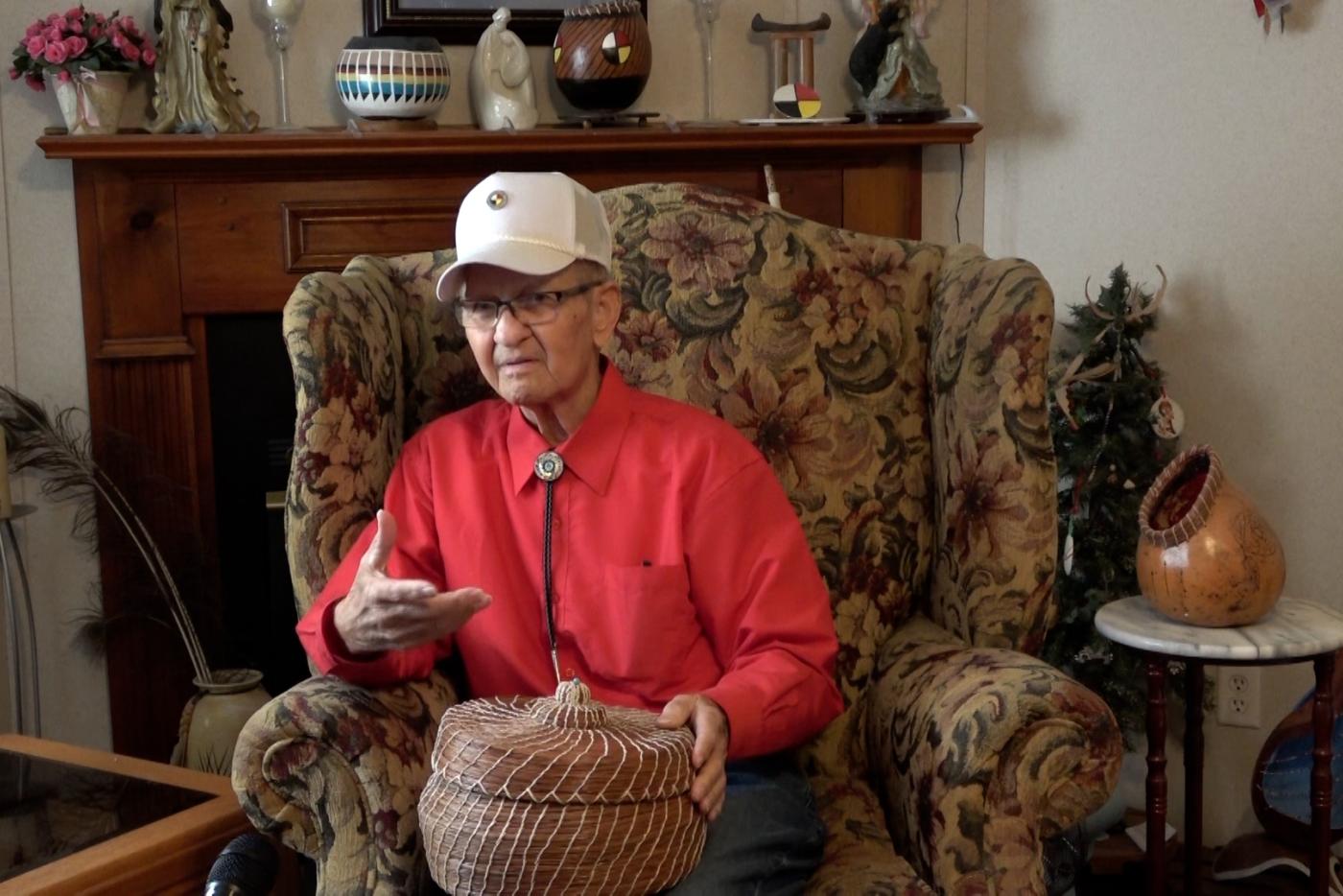 an older man sitting in a chair holding a basket 
