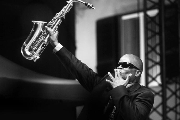 Musician Maceo Parker raising his saxophone in the air 