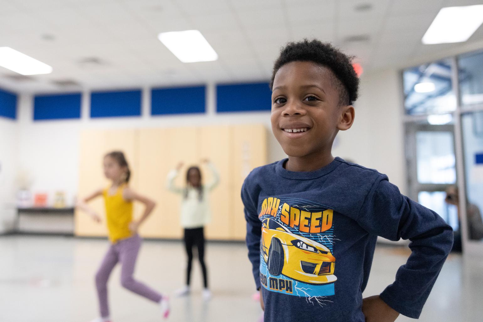 Kids in a dance classroom, with a smiling little boy standing in the foreground 