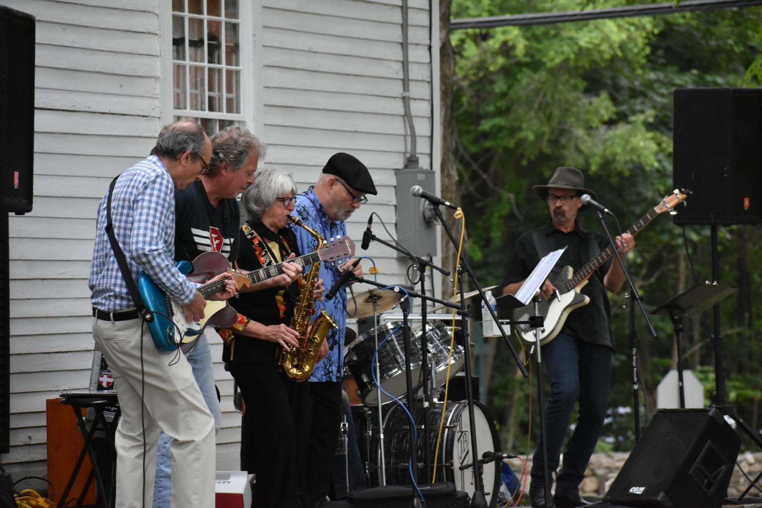 a band of older musicians playing a variety of instruments outdoor