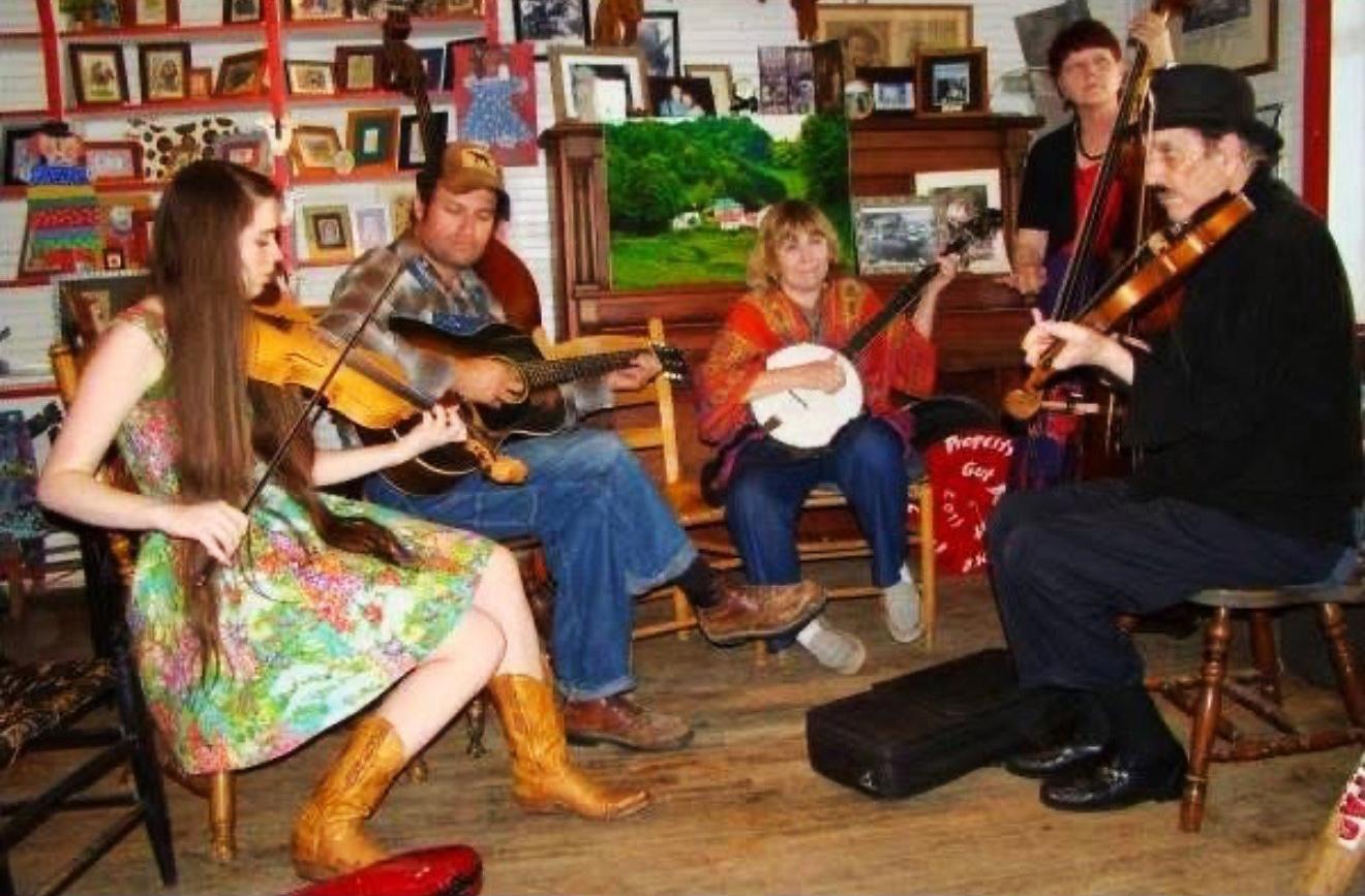 five people playing various instruments - guitar, banjo, violin, etc