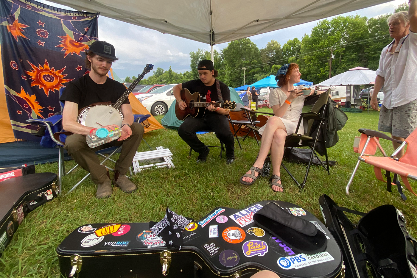 a group of people under a tent on a law playing music on banjos and guitars