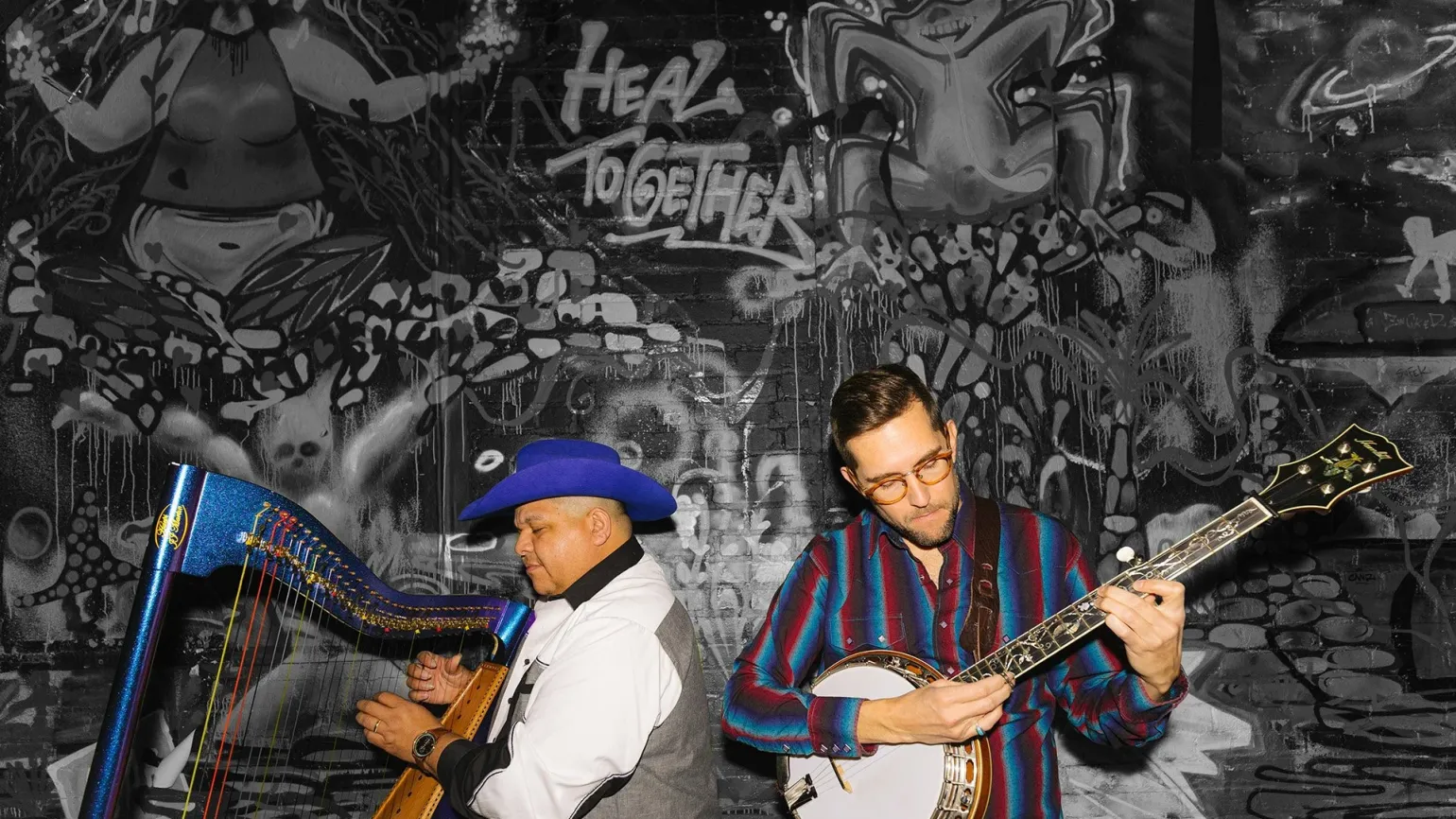 two musicians, one playing a harp, the other a banjo. photo by Tommy Coyote