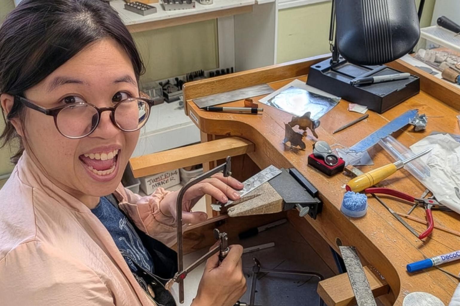 An artist working on metalwork with a small jigsaw.