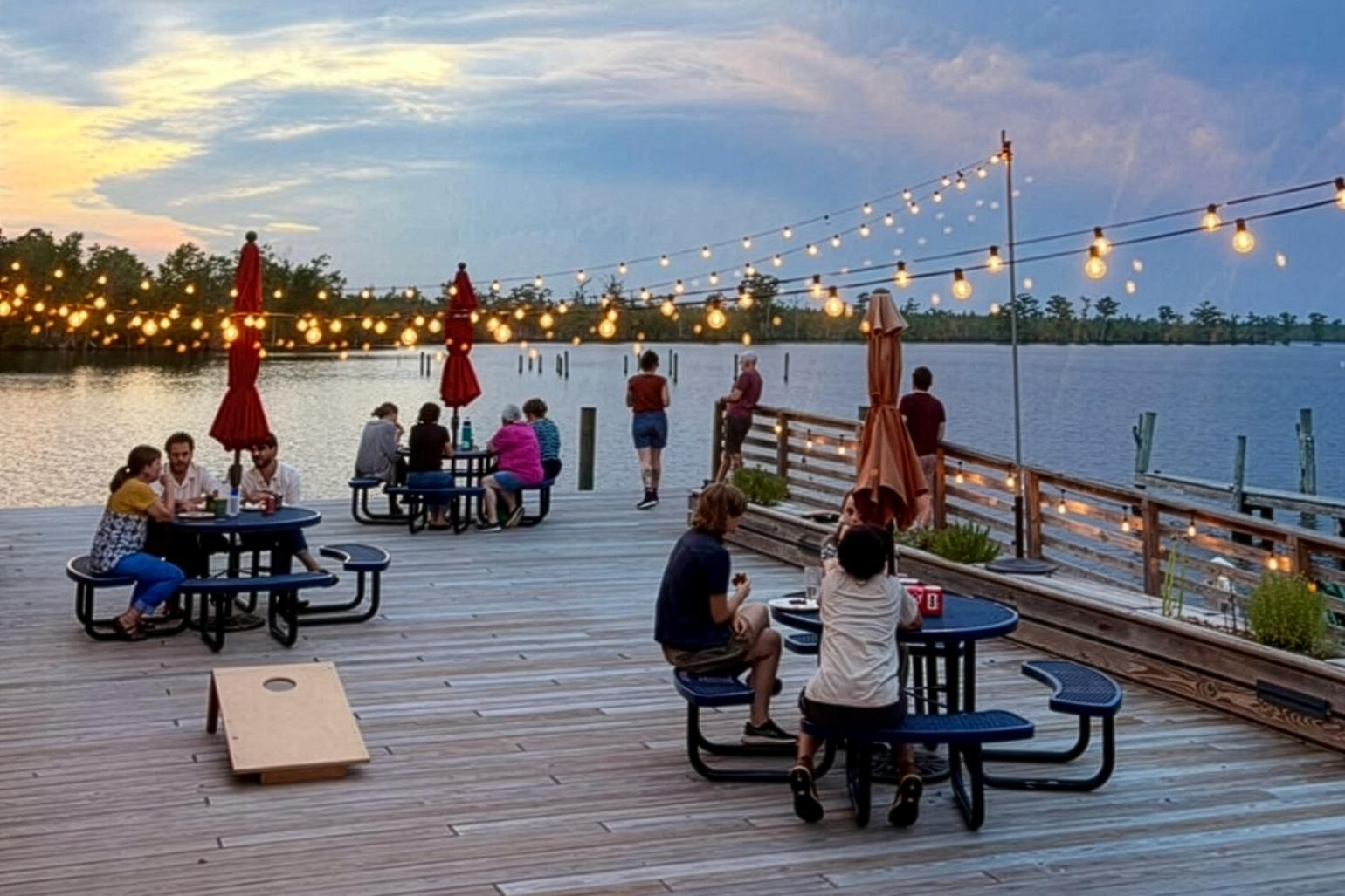 People eating at picnic tables along the Scuppernong River. Photo by Sarah Grace Cheek, courtesy of Pocosin Art School of Fine Craft.