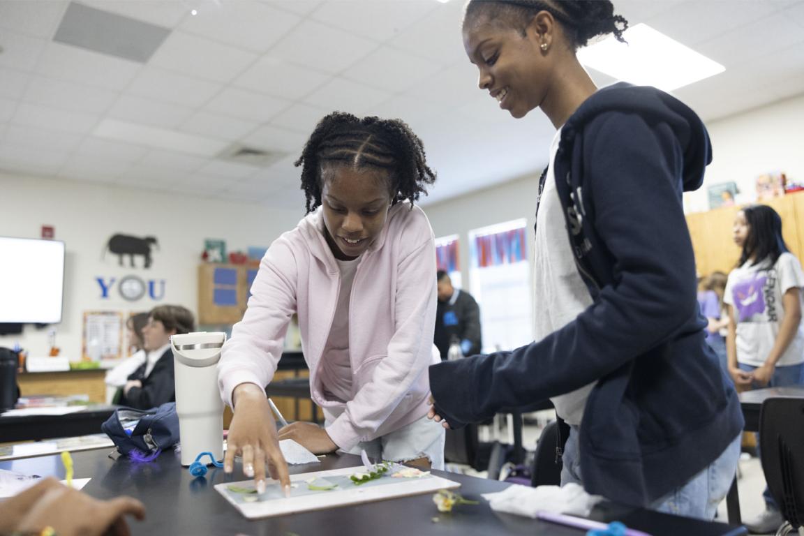 Two students work on a piece of artwork on a desk together. Photo by Tibor Nemeth, courtesy of North Carolina Arts Council