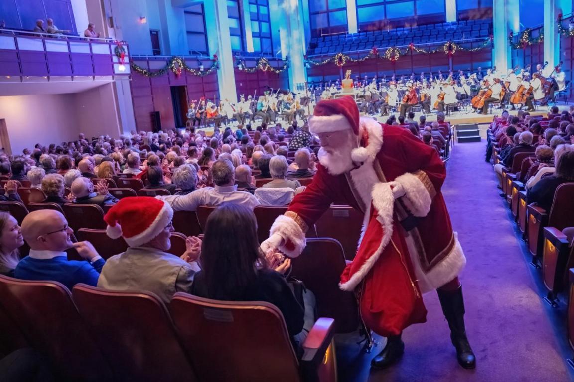 A Santa hands out presents in a filled concert hall