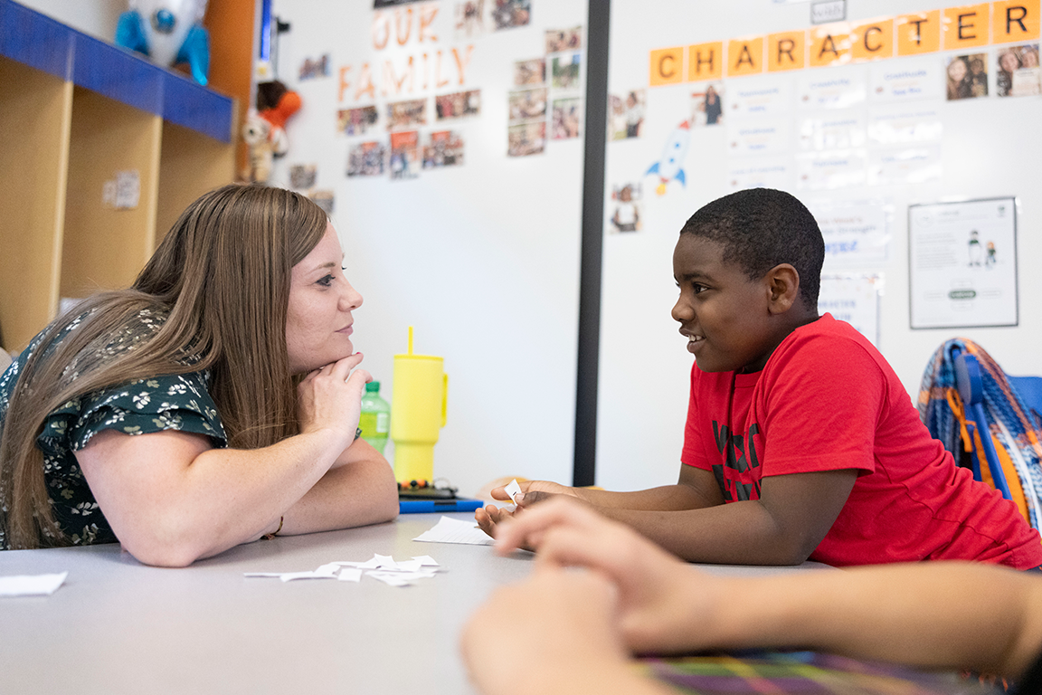 Teacher and student sitting at a desk chatting to each other