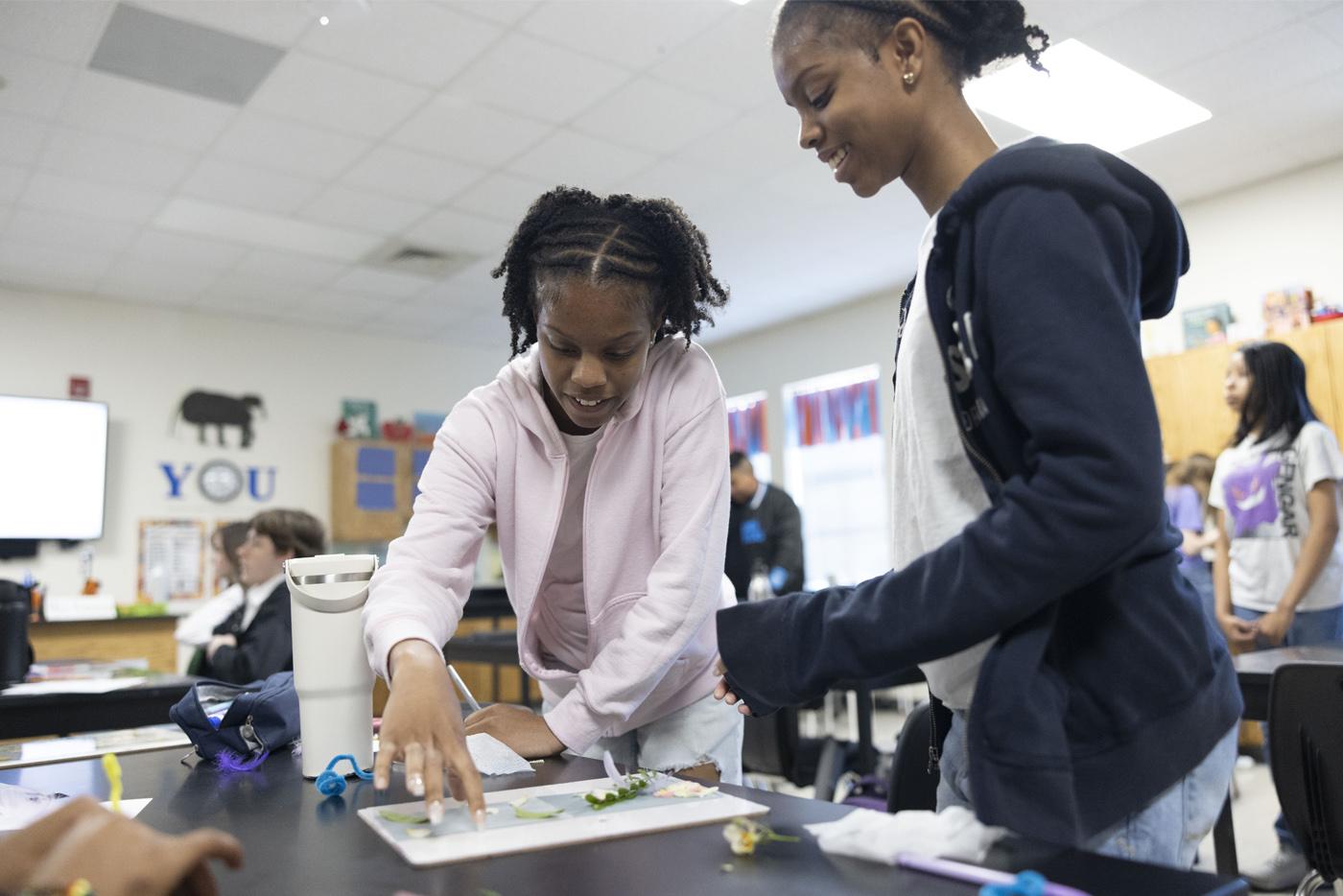 Two students work on a piece of artwork on a desk together. Photo by Tibor Nemeth, courtesy of North Carolina Arts Council