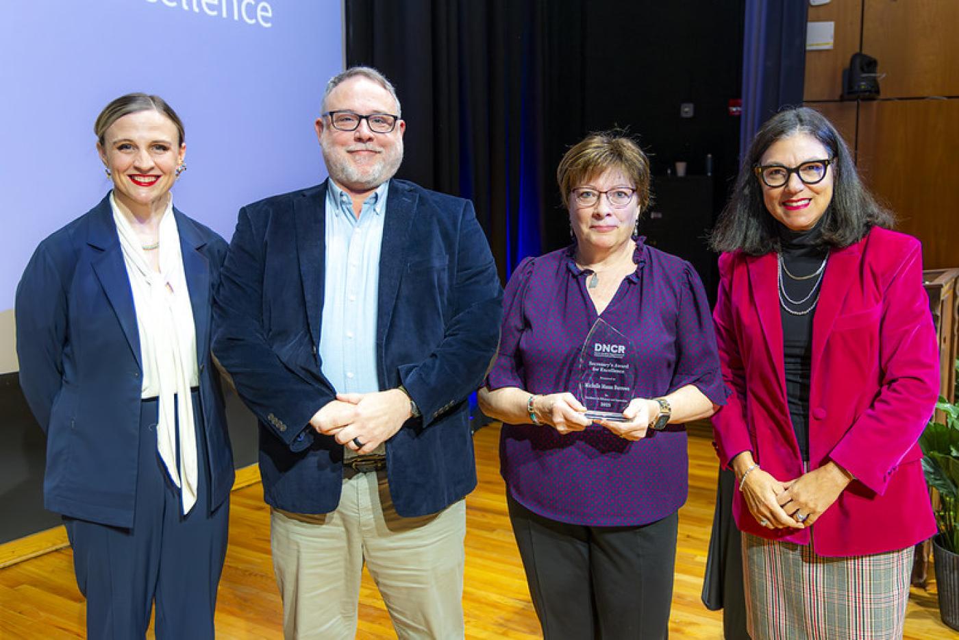 Michelle Burrows on stage at the DNCR auditorium receiving the Secretary's Award of Excellence
