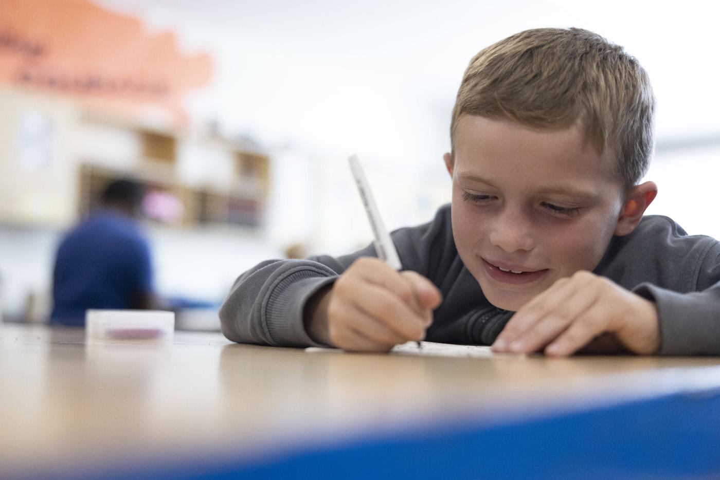 A student writing on a paper at a desk. 