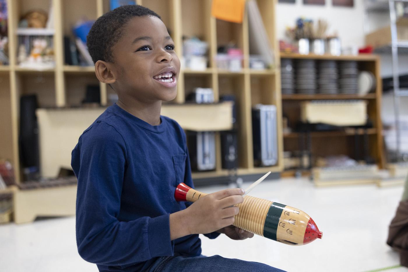 A little boy plays a percussion instrument.