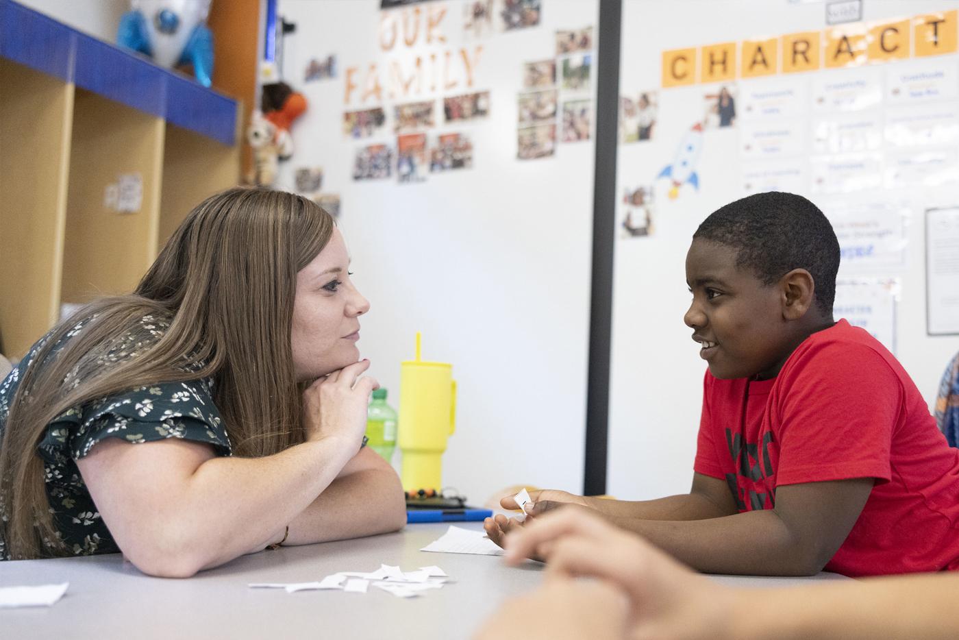 Teacher leaning forward and speaking with a student.